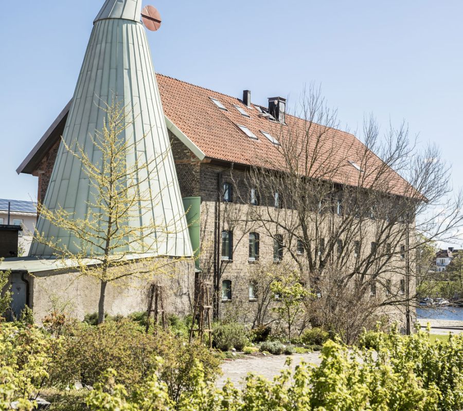 Ett stort tegelhus och en torkria i ljusgrönt intill.